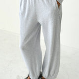 Person wearing gray sweatpants and polka dot shoes on a white background