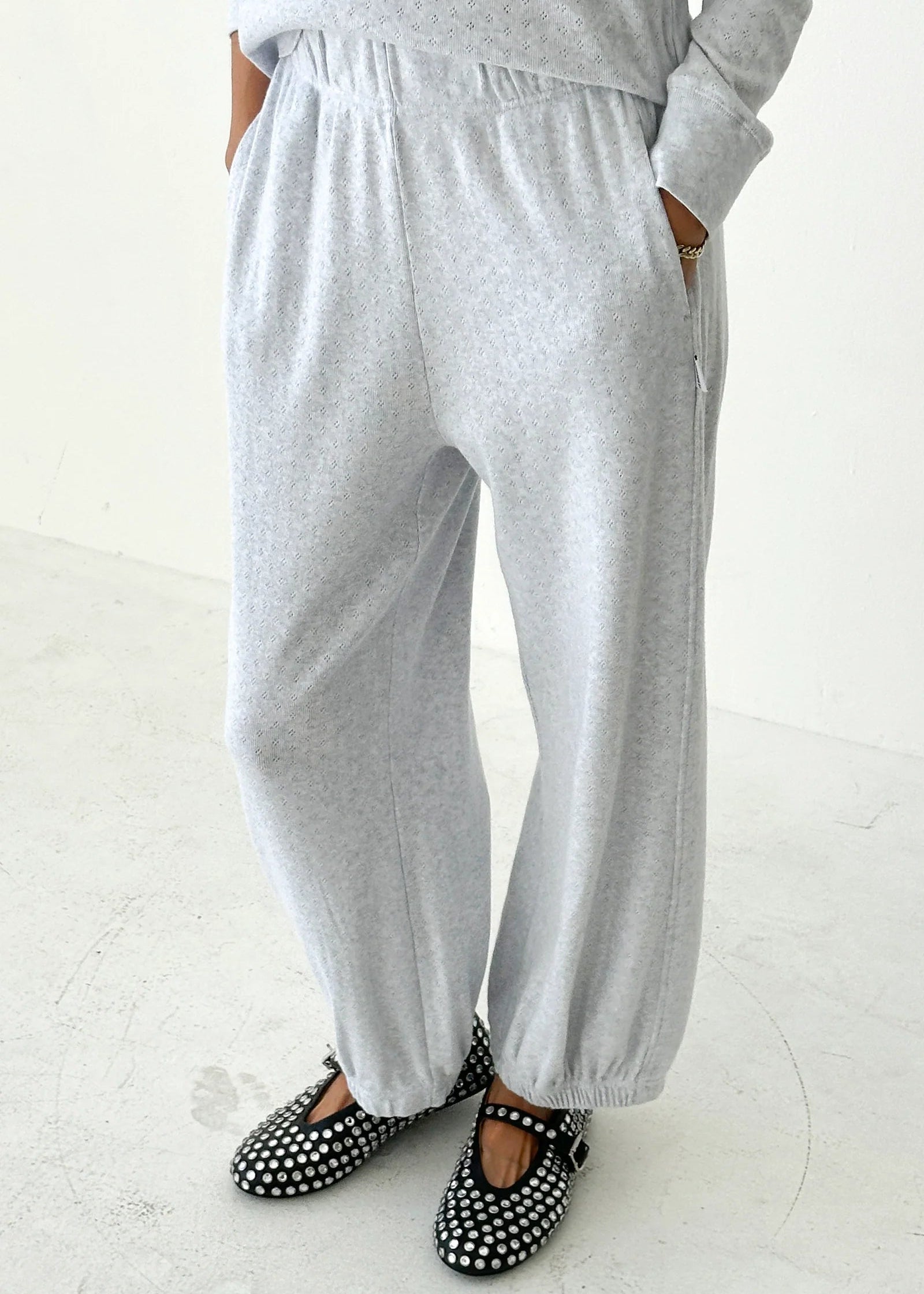 Person wearing gray sweatpants and polka dot shoes on a white background