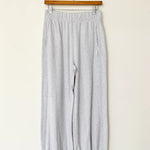 Gray pants hanging on a wooden hanger against a white wall