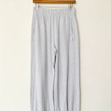 Gray pants hanging on a wooden hanger against a white wall