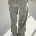 Person wearing gray sweatpants and blue shoes on a white floor.
