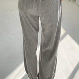 Person wearing gray sweatpants and blue shoes on a white floor.