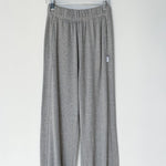 Gray sweatpants hanging on a wooden hanger against a white background
