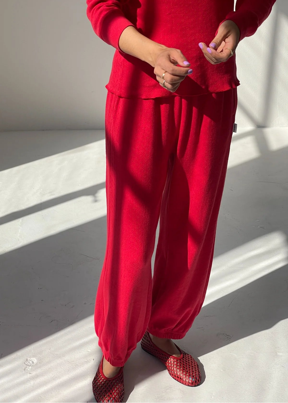 Person wearing a red outfit with matching shoes on a light background