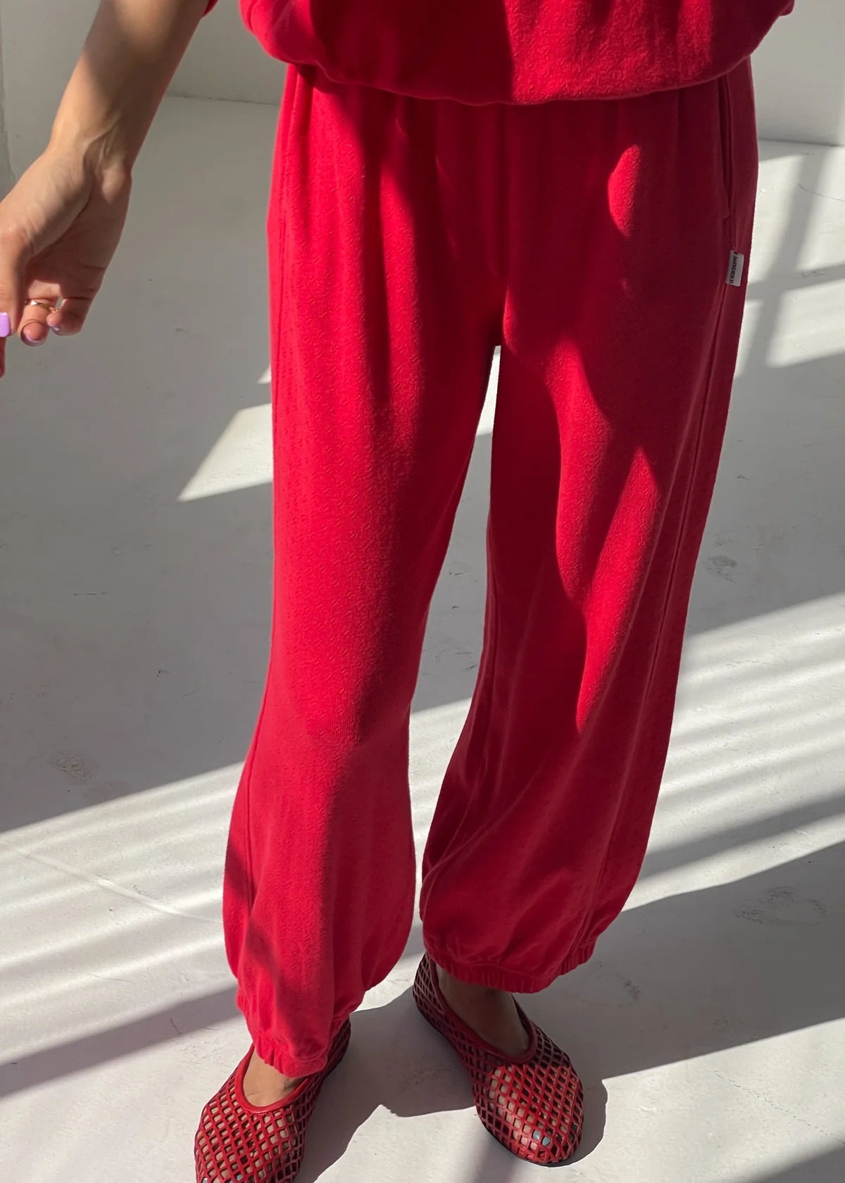 Person wearing a red outfit with matching shoes on a light background