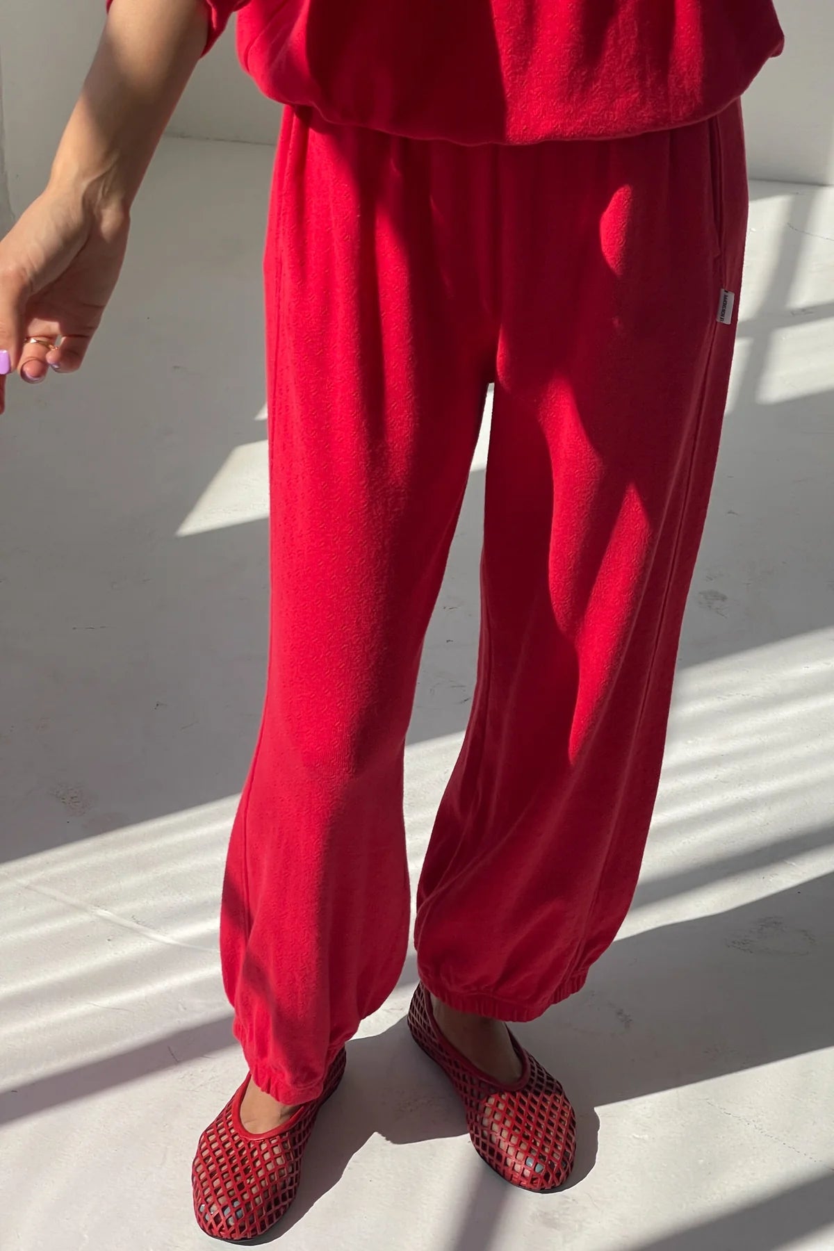 Person wearing a red outfit with matching shoes on a light background