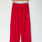 Red pants hanging on a wooden hanger against a white background