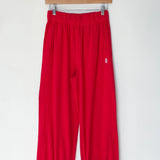 Red pants hanging on a wooden hanger against a white background