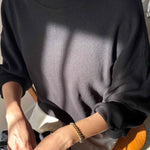 Person wearing a black sweatshirt sitting on a chair with a neutral background