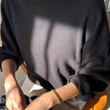 Person wearing a black sweatshirt sitting on a chair with a neutral background