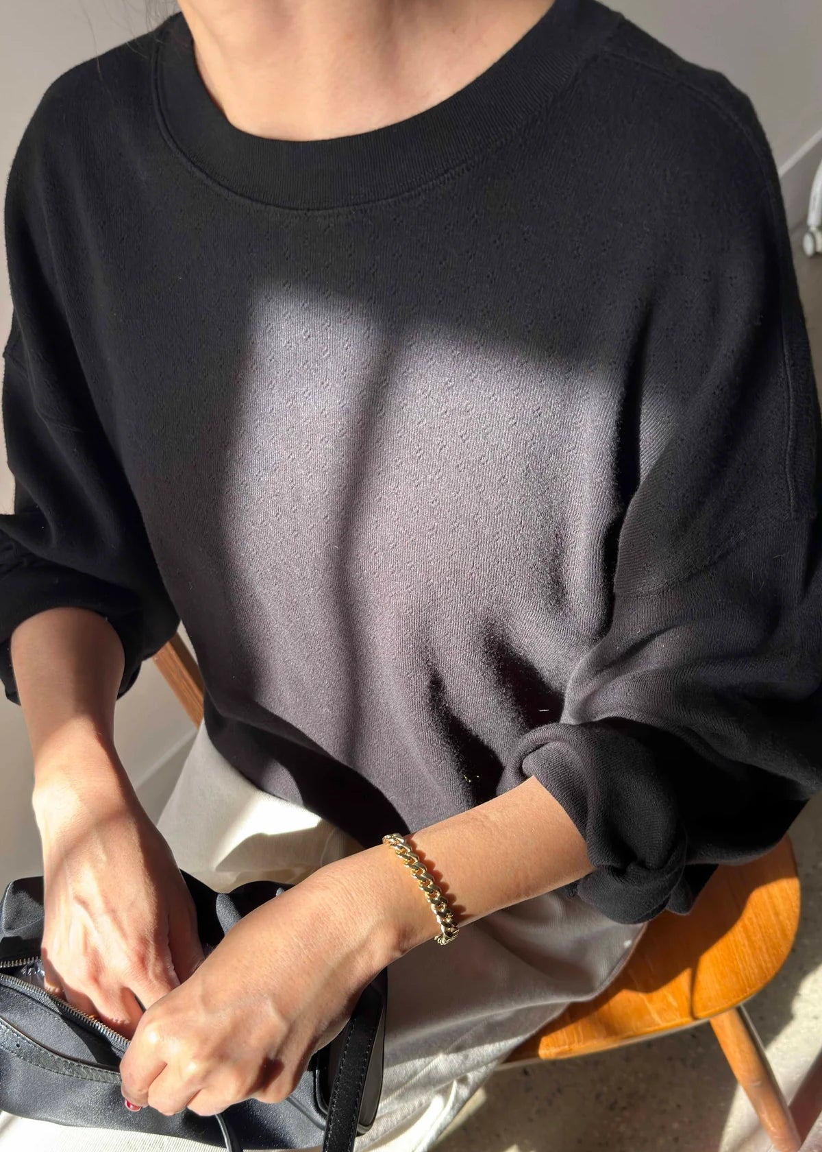 Person wearing a black sweatshirt sitting on a chair with a neutral background
