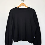 Black sweatshirt on a wooden hanger against a white background