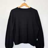 Black sweatshirt on a wooden hanger against a white background