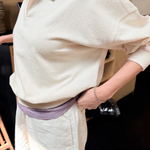 Person wearing a light-colored outfit with a collar, standing indoors.