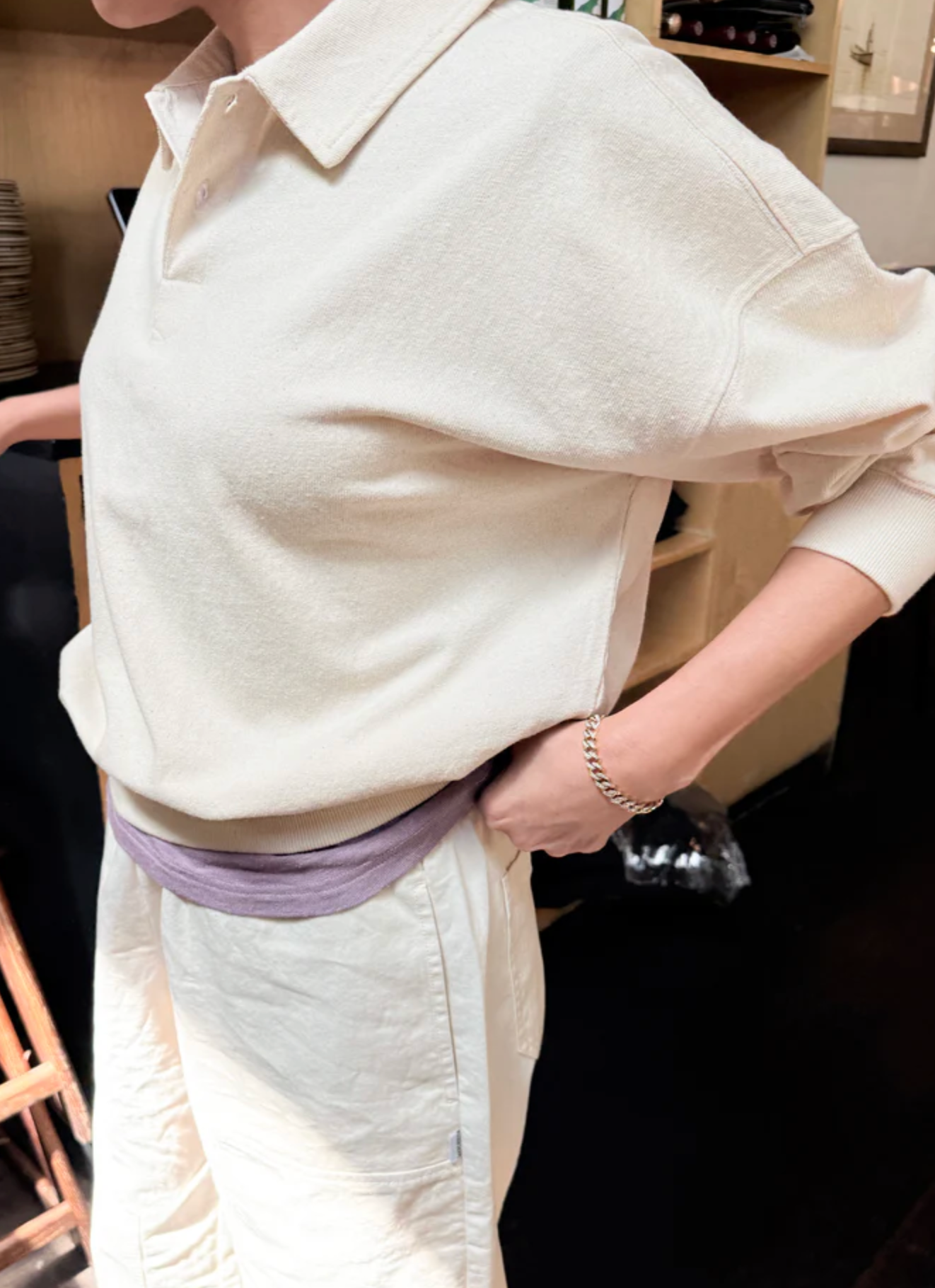 Person wearing a light-colored outfit with a collar, standing indoors.