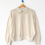 Beige sweater on a hanger against a white background