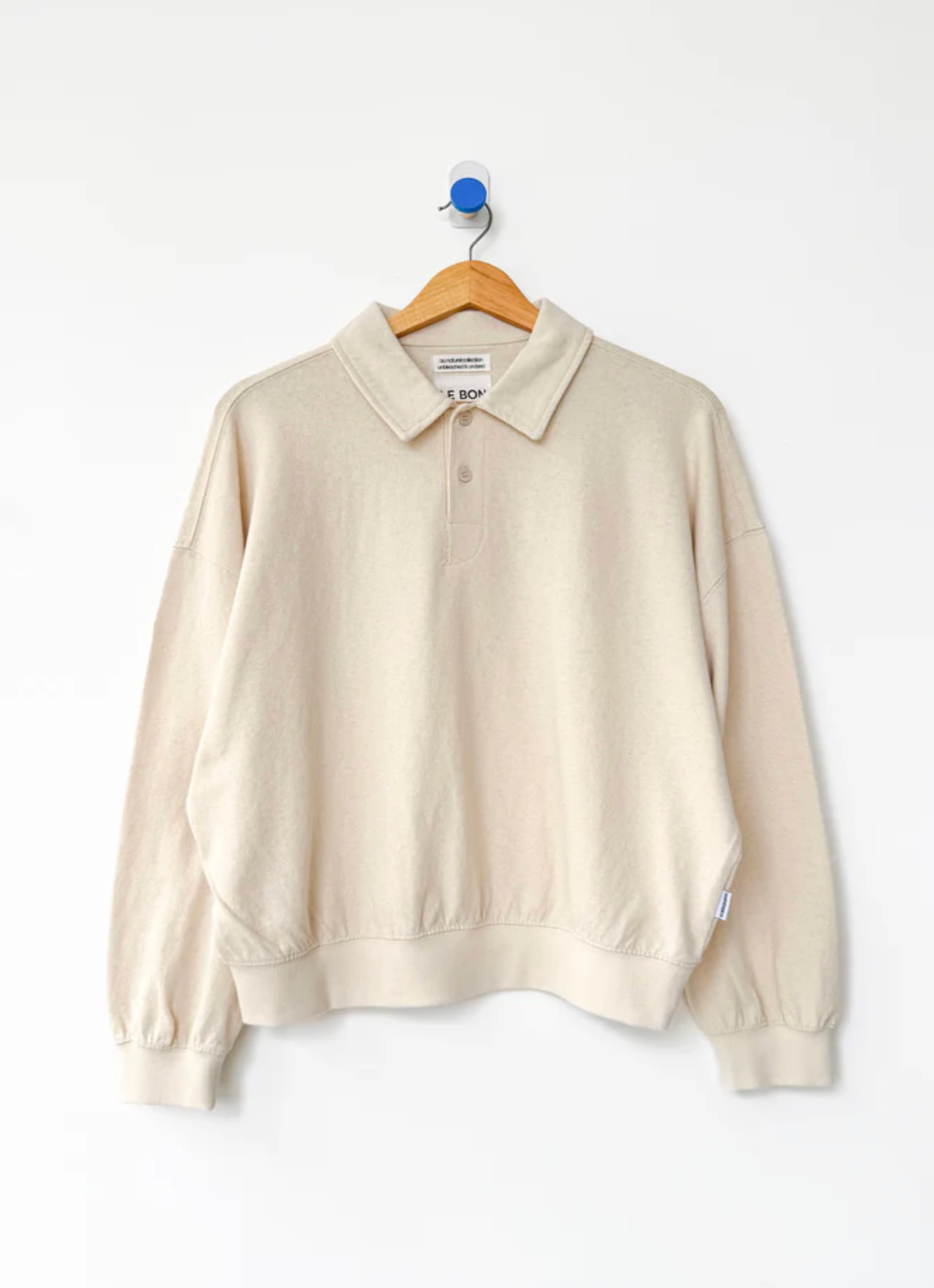 Beige sweater on a hanger against a white background