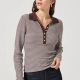 Woman wearing a striped shirt with a brown collar on a plain background