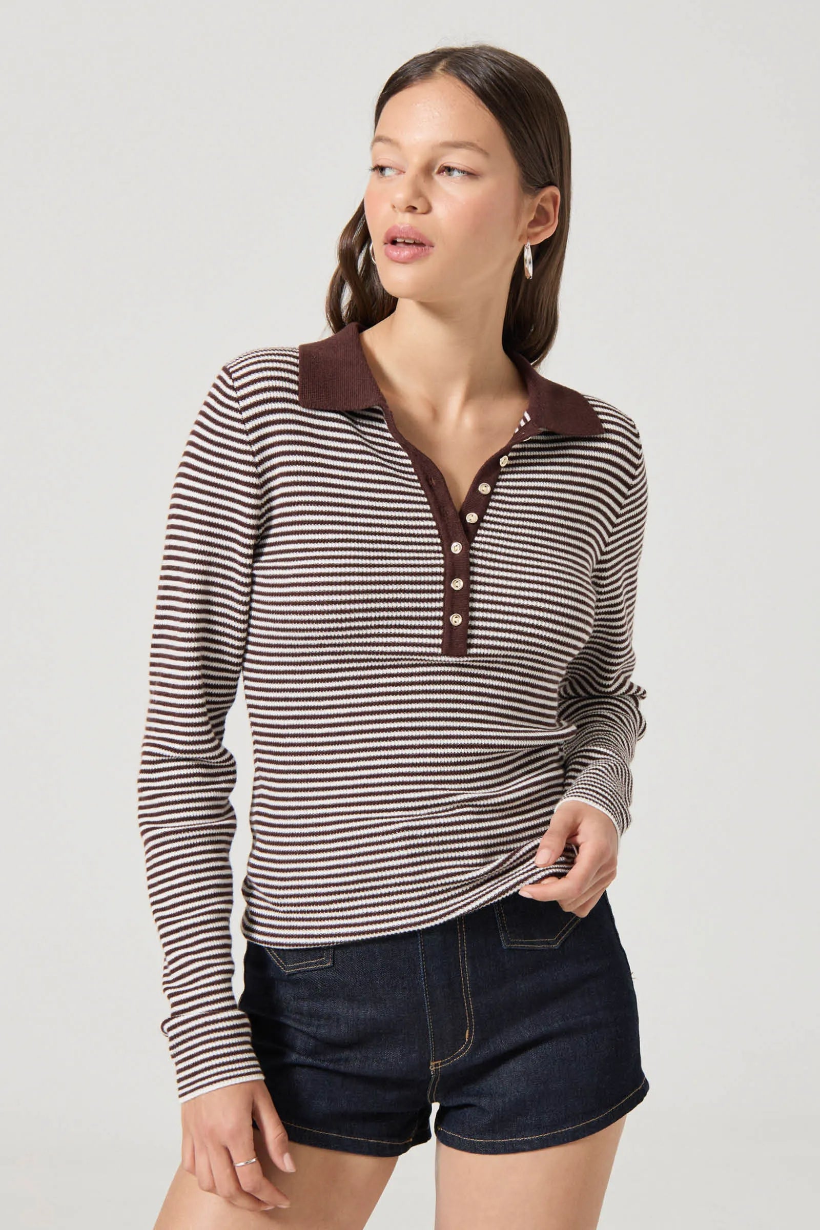 Woman wearing a striped shirt with a brown collar on a plain background