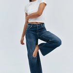 Woman wearing a white t-shirt and blue jeans on a light gray background