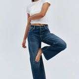 Woman wearing a white t-shirt and blue jeans on a light gray background