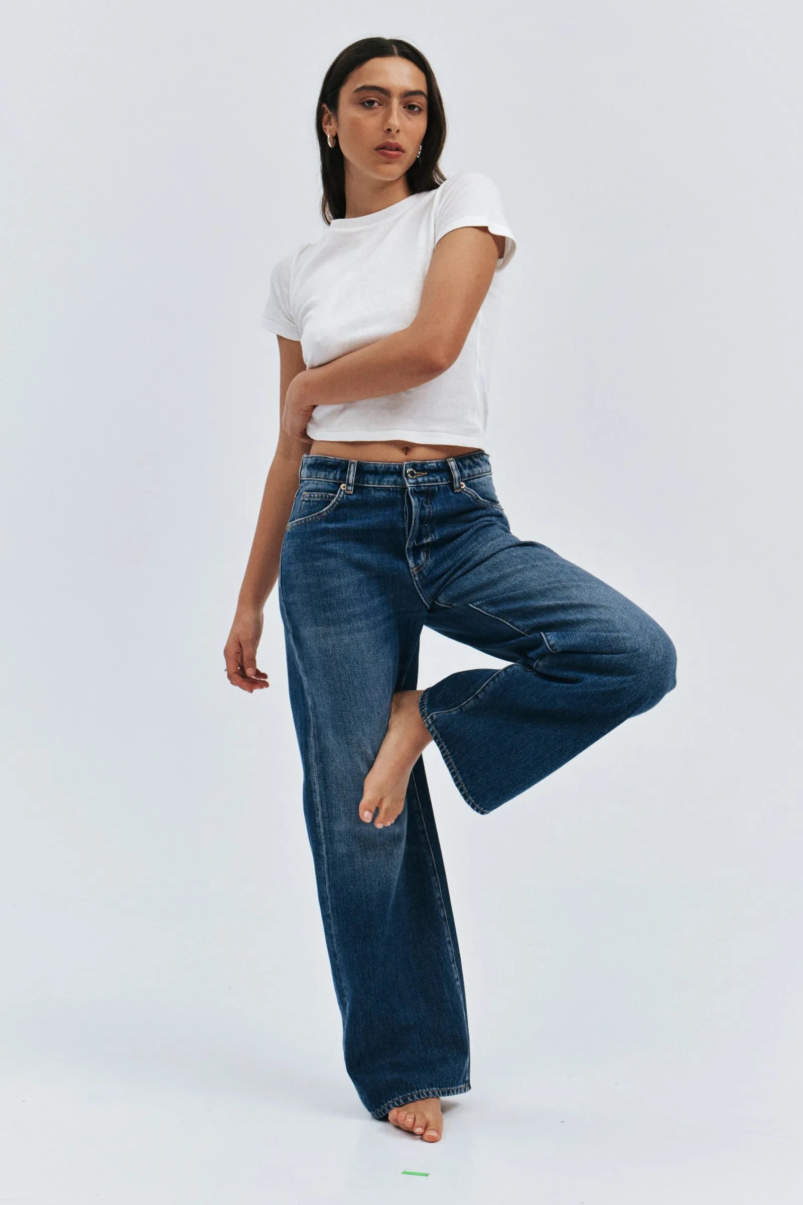 Woman wearing a white t-shirt and blue jeans on a light gray background
