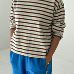 Person wearing a striped shirt and blue pants on a white background