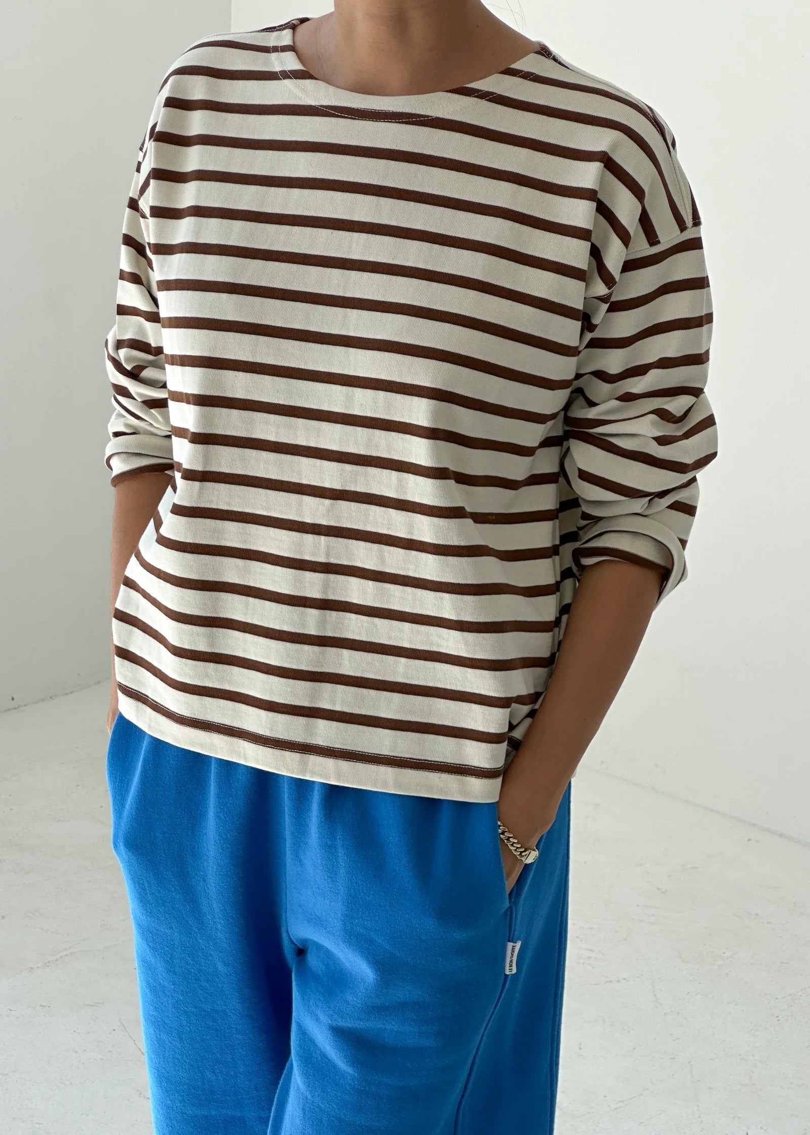Person wearing a striped shirt and blue pants on a white background