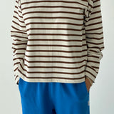 Person wearing a brown and white striped shirt with blue pants on a plain background