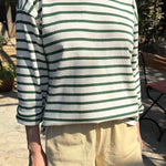 Person wearing a green and white striped shirt with beige shorts outdoors.