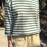 Person wearing a green and white striped shirt with beige shorts outdoors.
