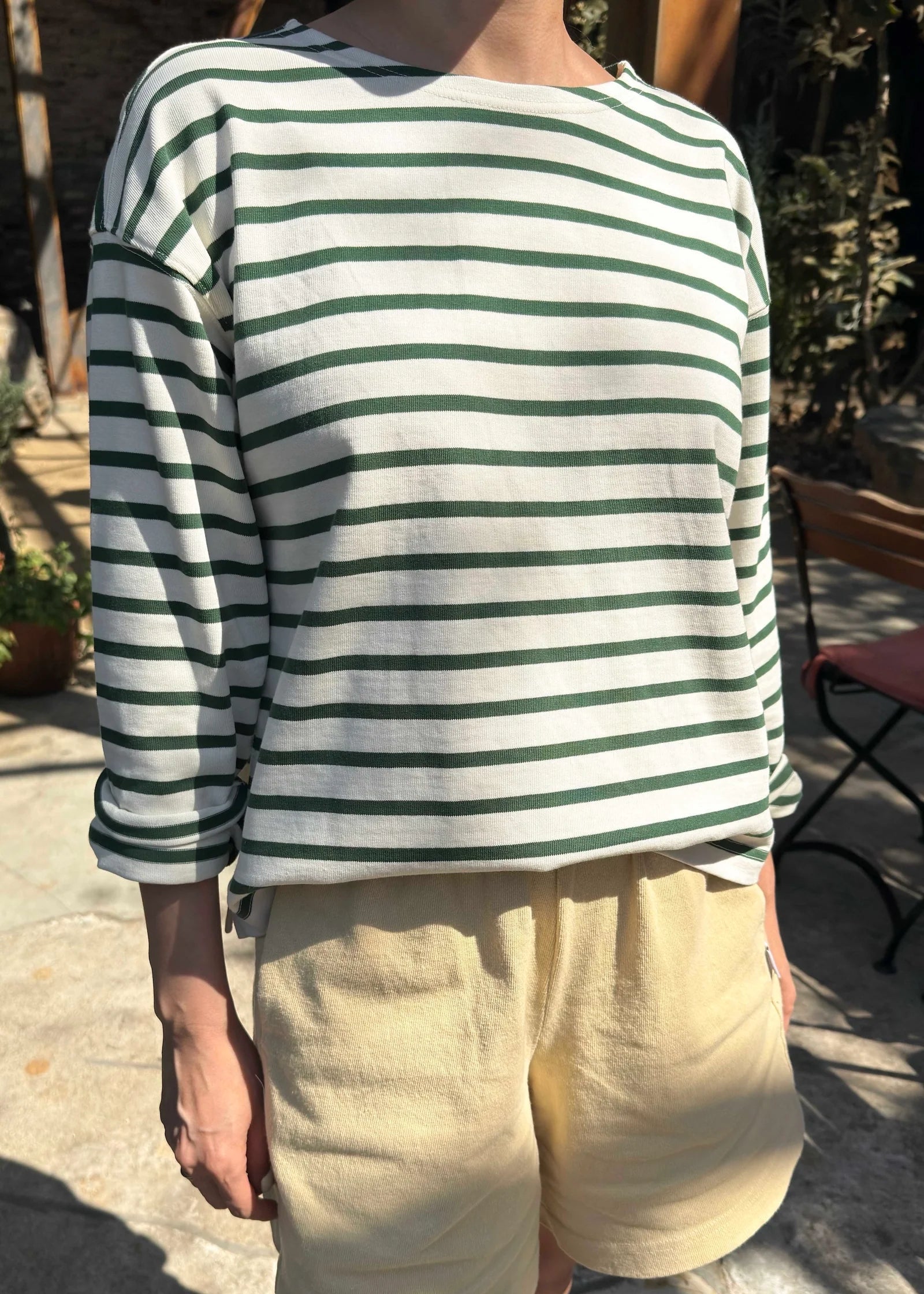 Person wearing a green and white striped shirt with beige shorts outdoors.