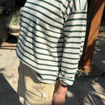 Person wearing a green and white striped shirt and beige shorts outdoors.