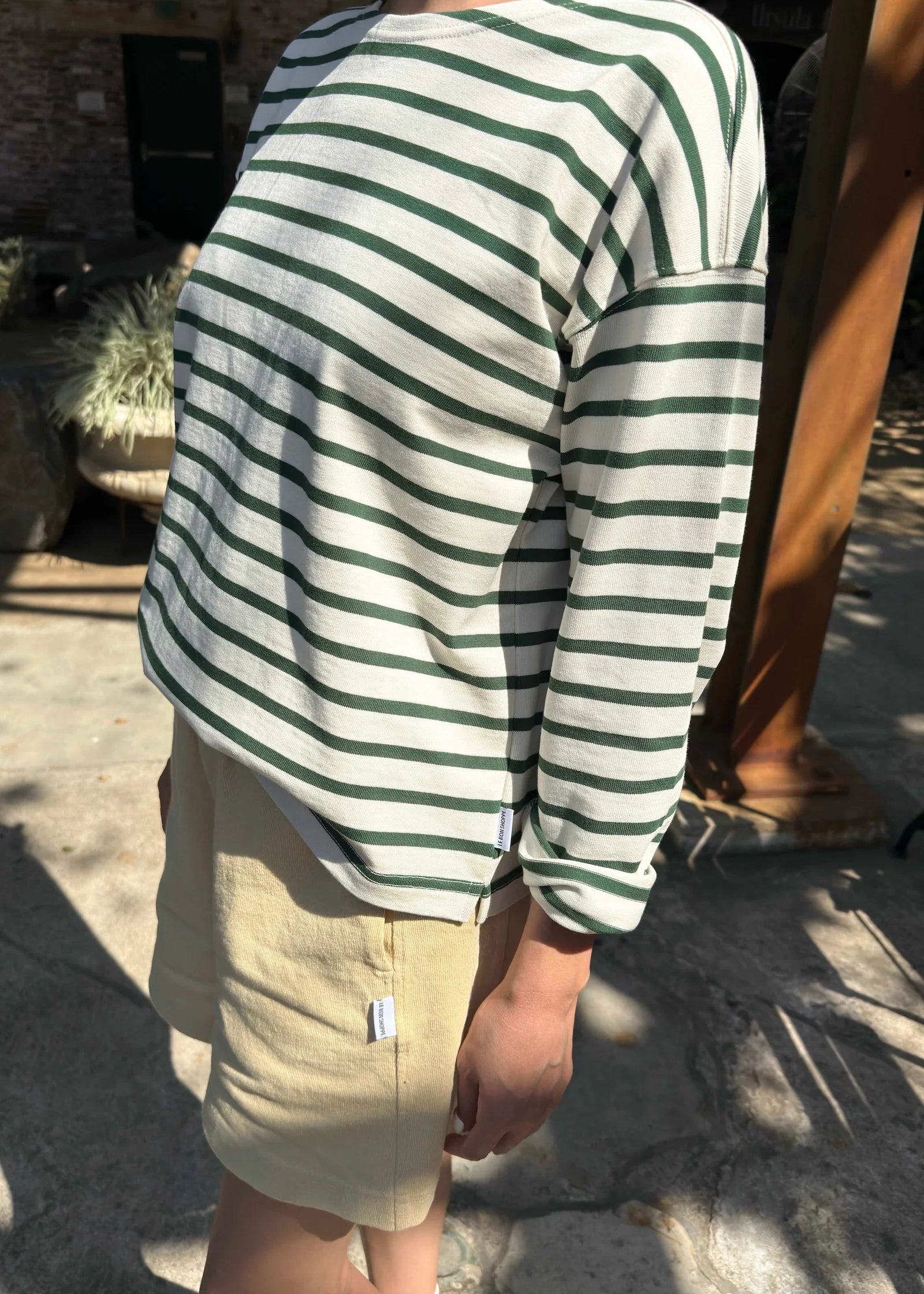 Person wearing a green and white striped shirt and beige shorts outdoors.