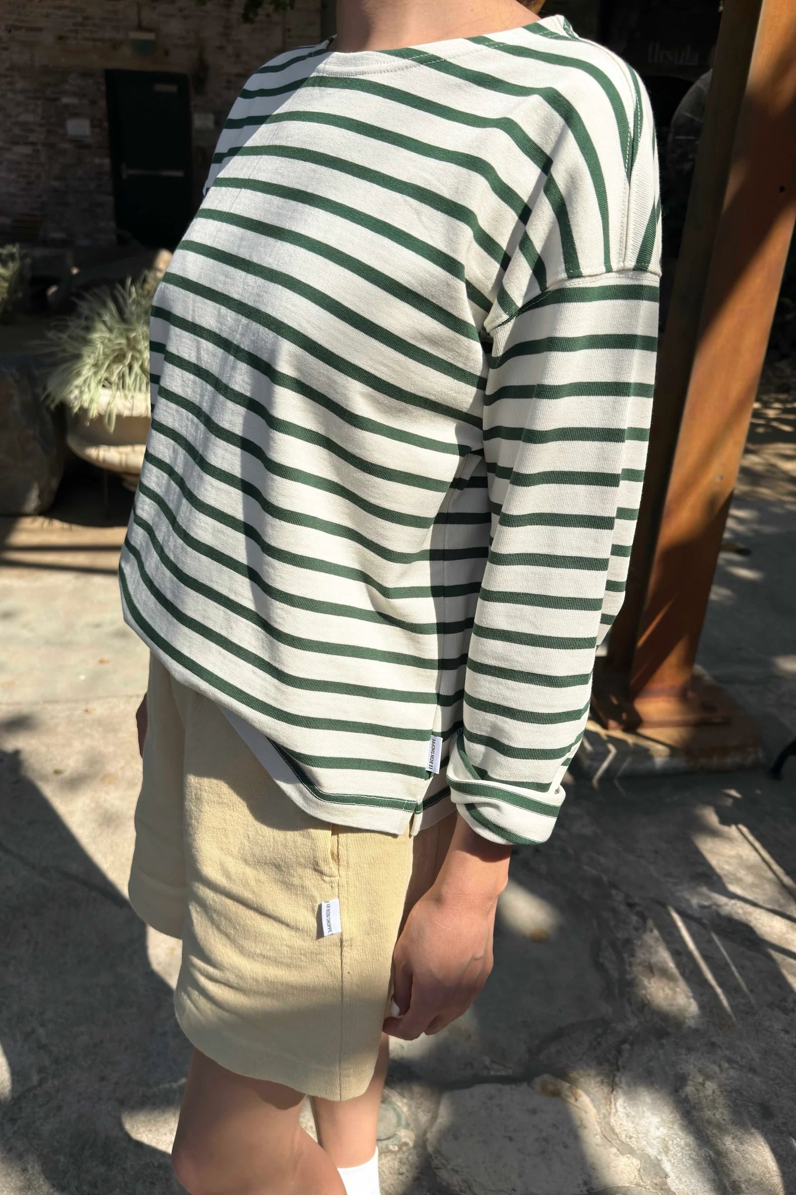 Person wearing a green and white striped shirt and beige shorts outdoors.