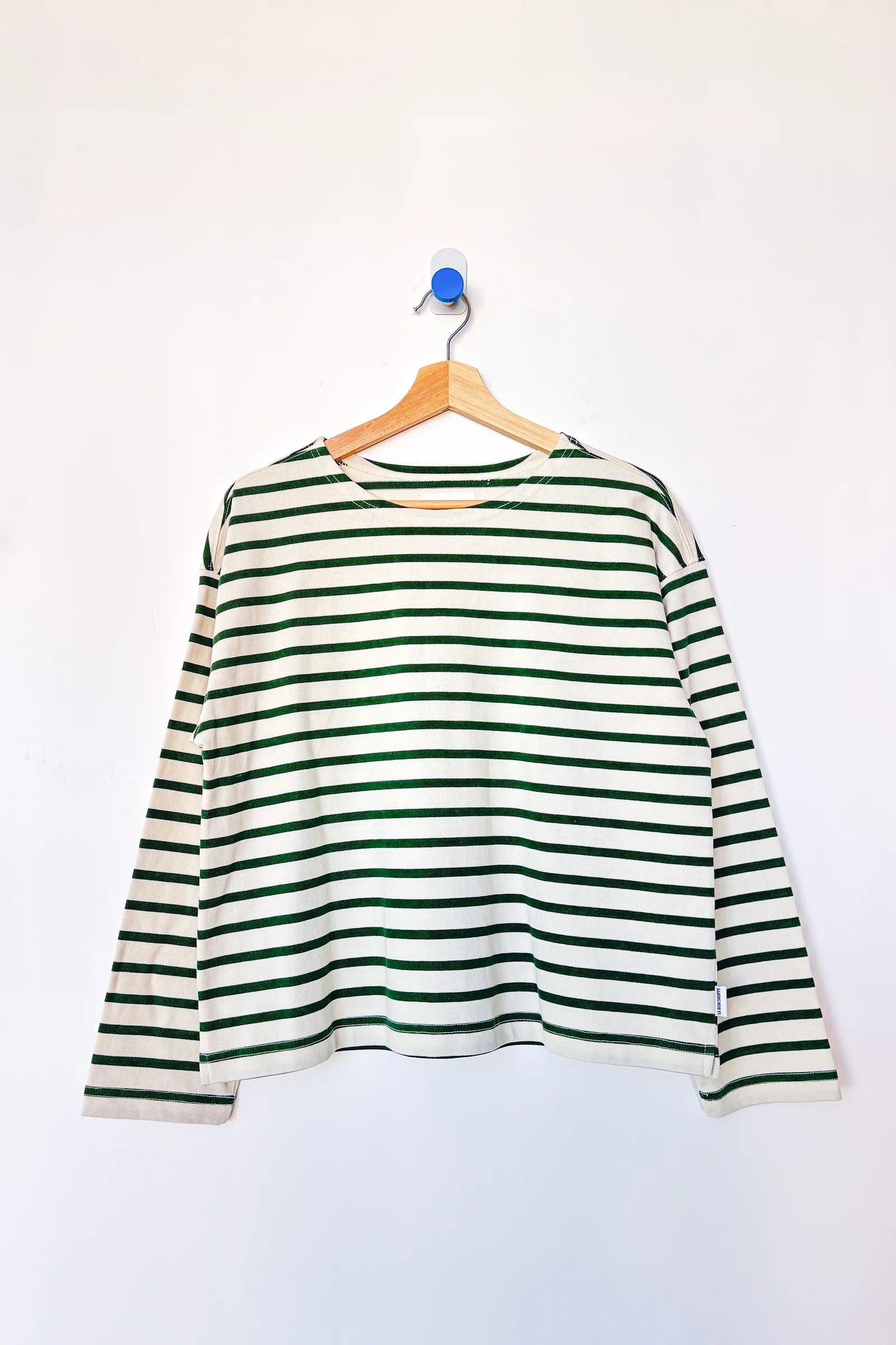 Green and white striped shirt on a hanger against a white background