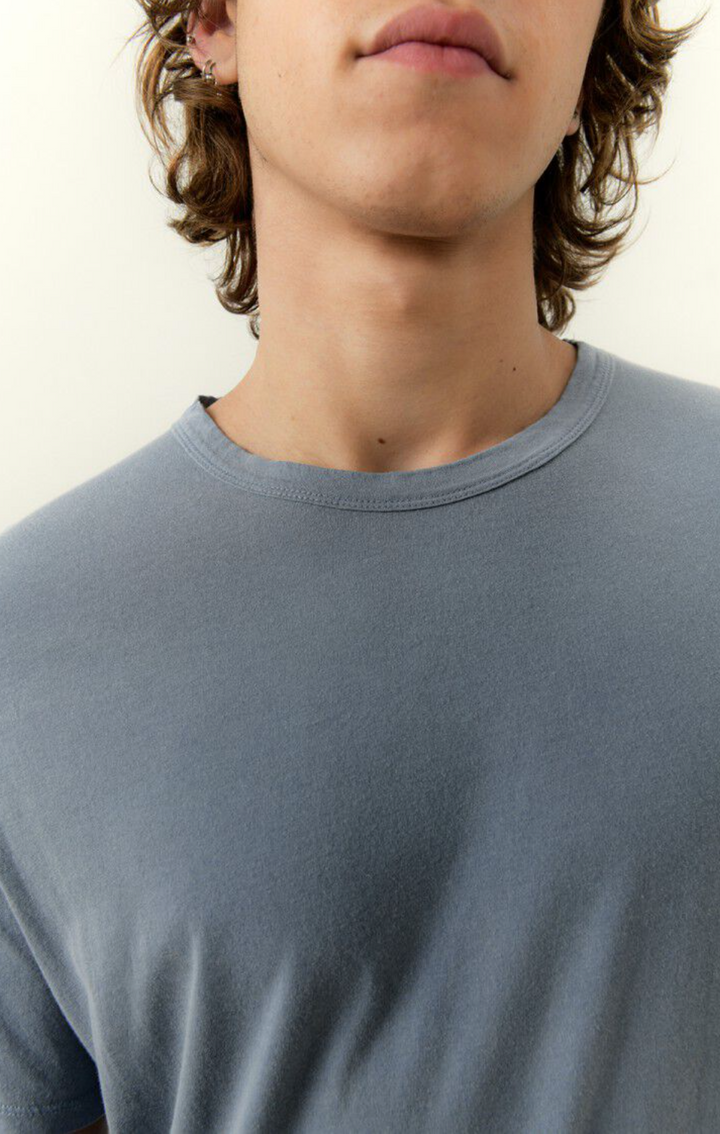 A close up neckline detail image of a male model wearing the devon tee shirt in vintage blue with white denim 