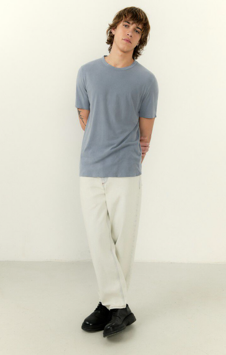 A full body image of a male model wearing the devon tee shirt in vintage blue and white denim 