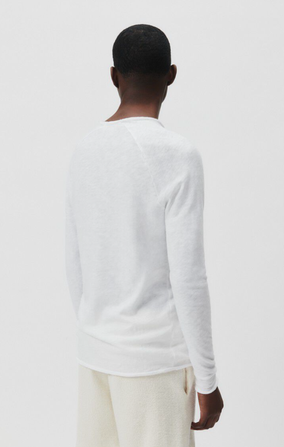 A medium close image showing the backside of a male model standing at an angle wearing the Sonoma Long Sleeve in white