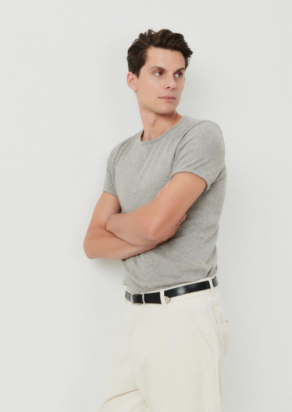 A medium close image of a male model standing at an angle wearing the Sonoma tee shirt in grey. 
