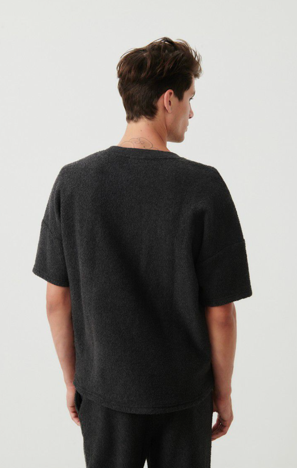 A medium close image of the backside of a male model wearing the bobypark tee shirt in anthracite