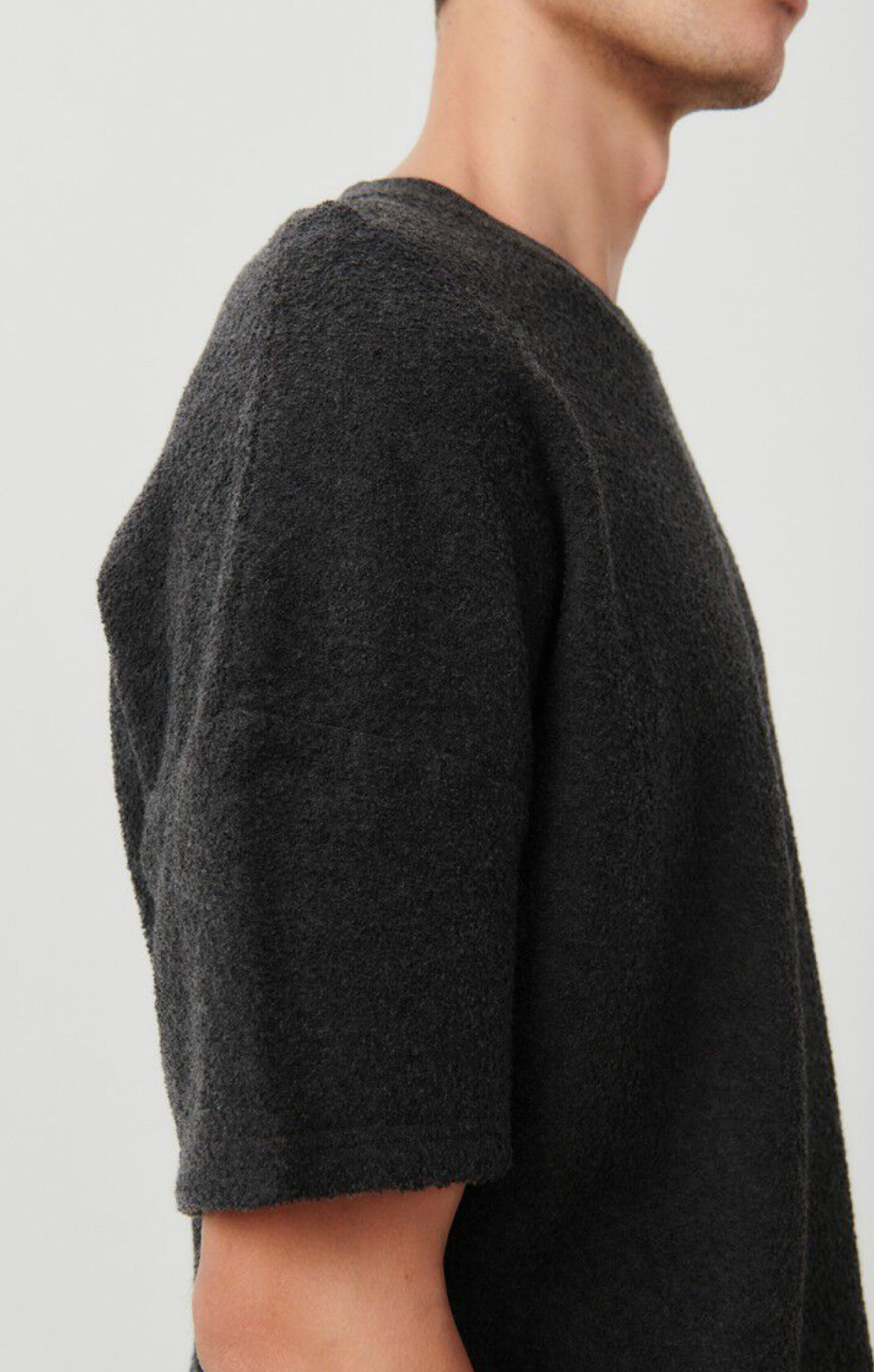 A close up sleeve detail image of a male model standing at an angle wearing the bobypark tee shirt in anthracite