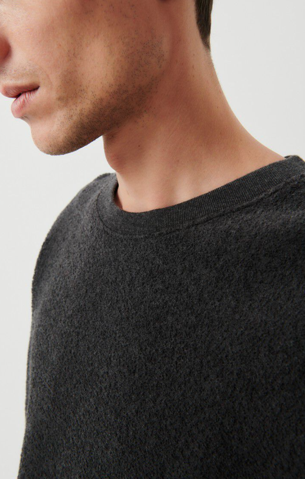 A close up neckline detail image of a male model standing at an angle wearing the bobypark tee shirt in anthracite