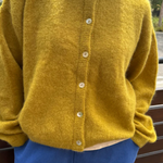 Person wearing a yellow cardigan and blue pants outdoors