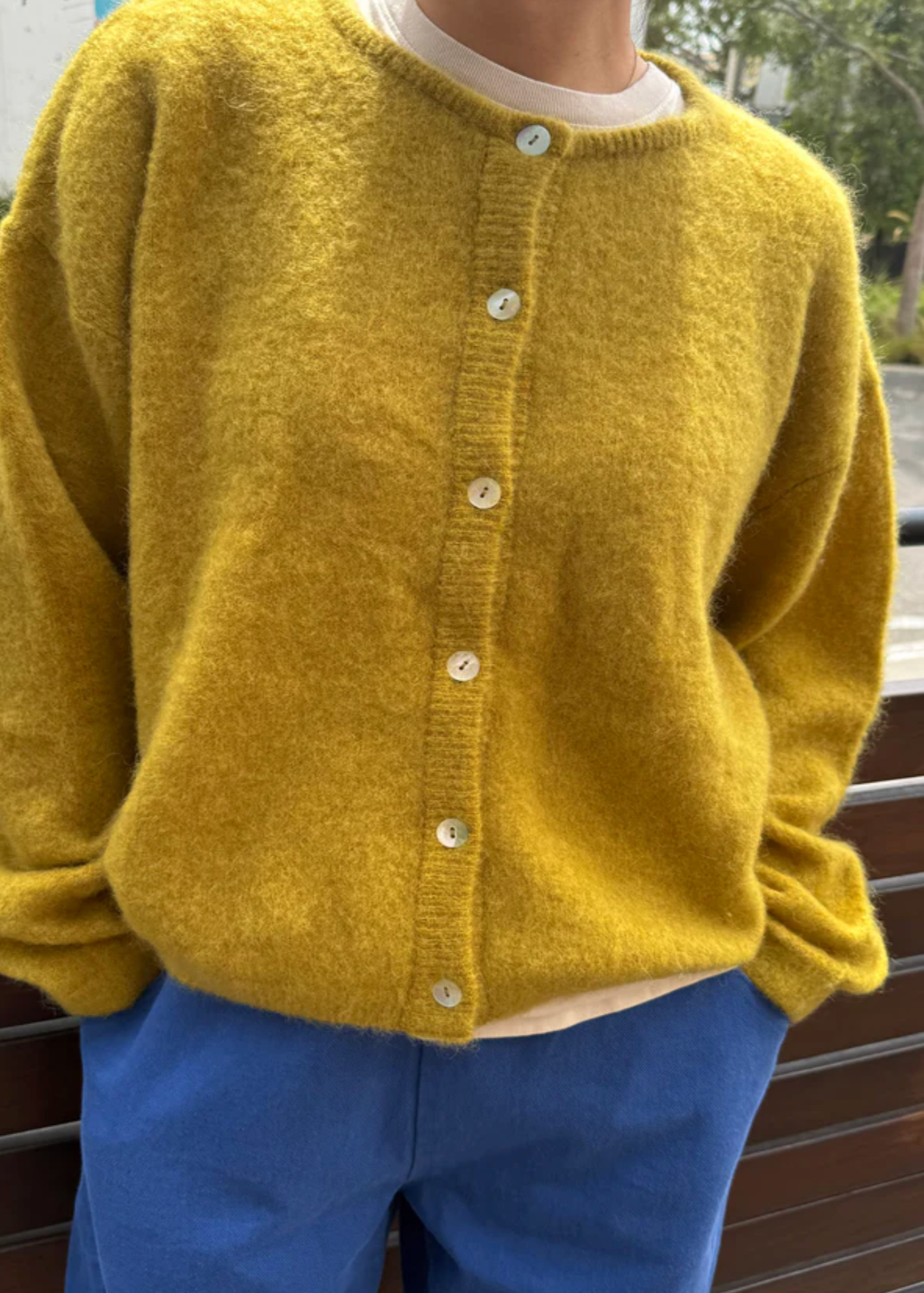 Person wearing a yellow cardigan and blue pants outdoors