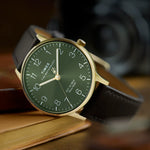 Timex watch with green dial and brown leather strap on a wooden surface