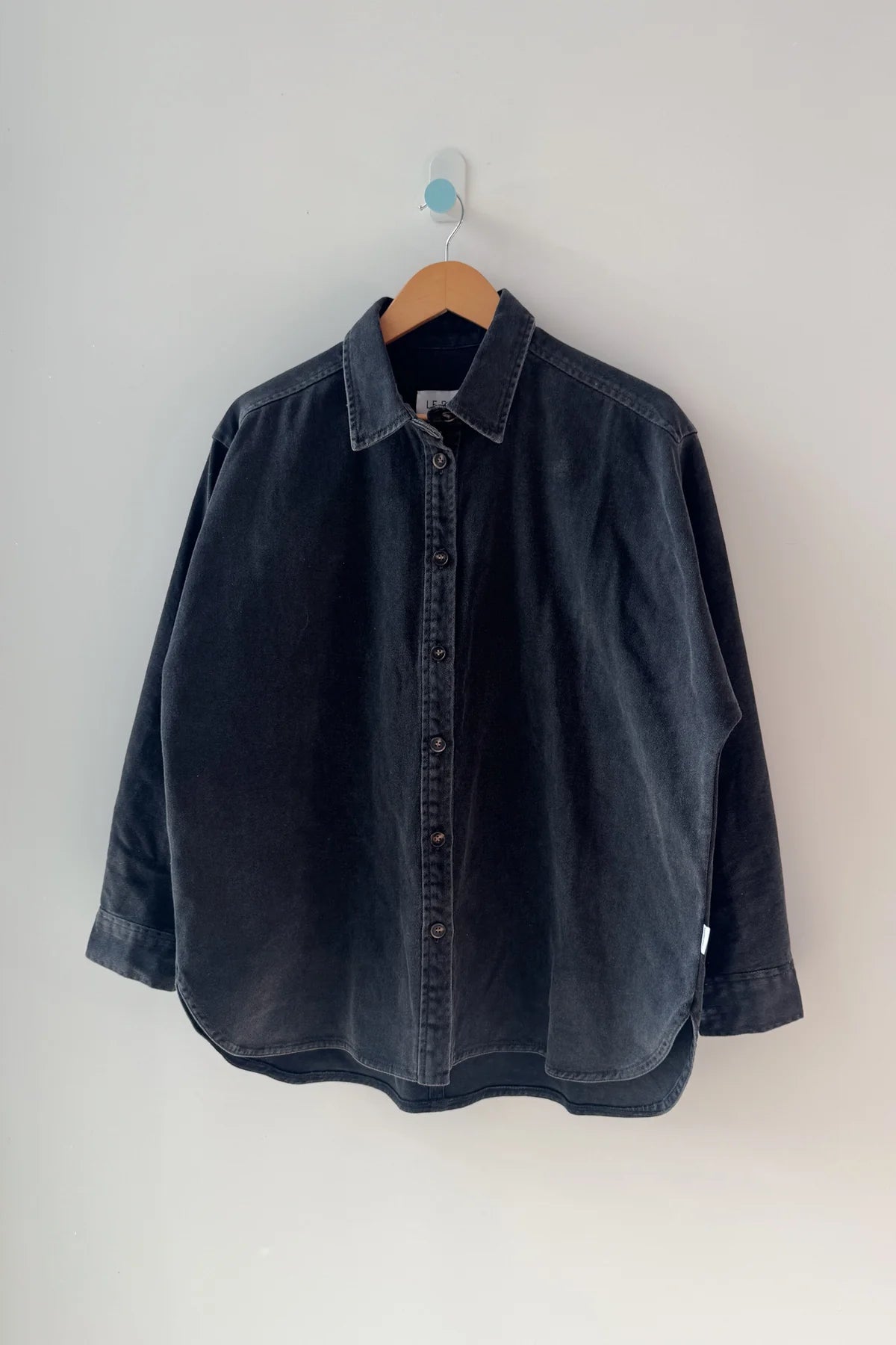 Dark denim shirt on a hanger against a white background