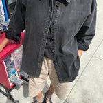 Person wearing a dark denim jacket on a city street.
