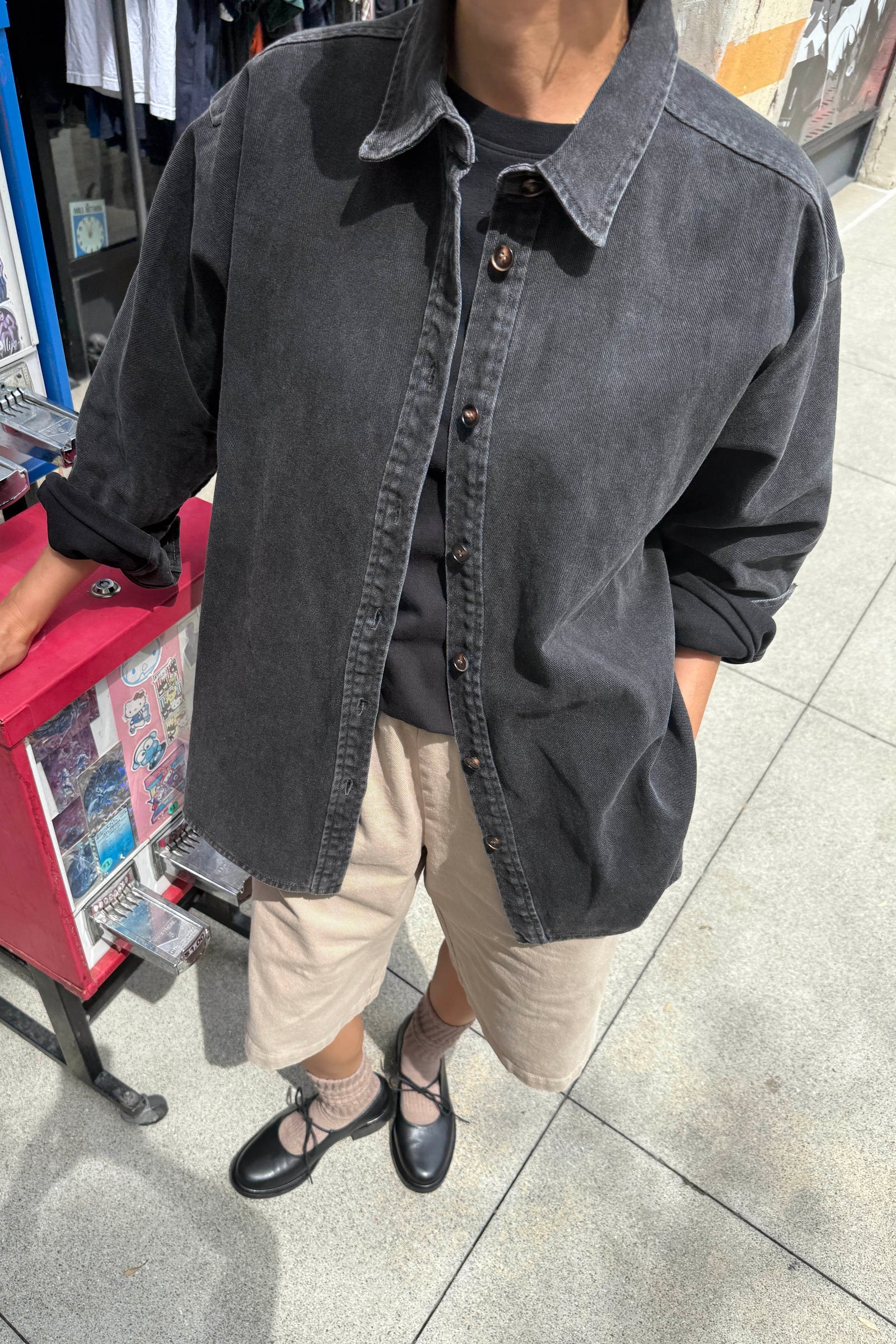 Person wearing a dark denim jacket on a city street.