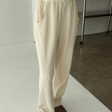 Person wearing beige corduroy pants and brown shoes on a white floor.